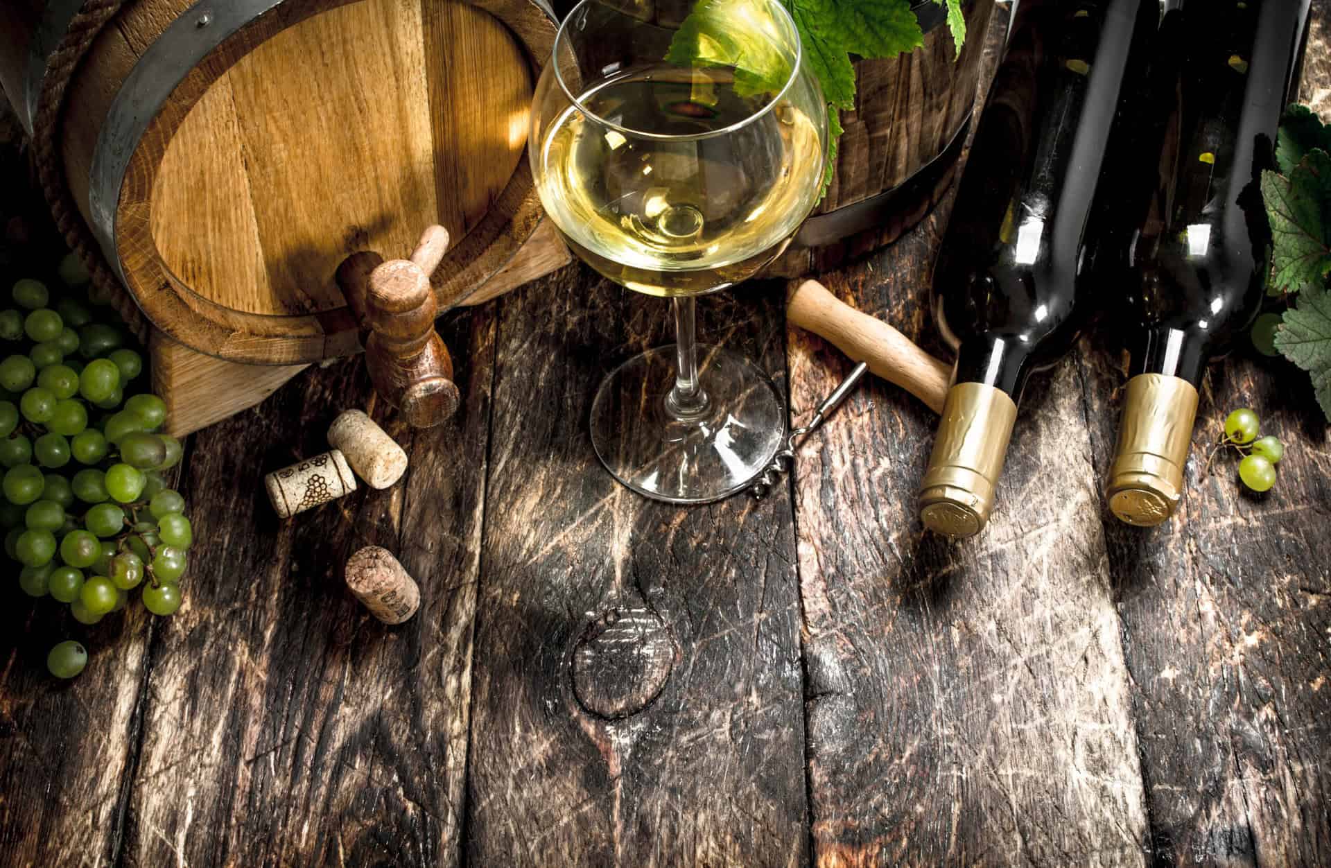 Wine background. A barrel of white wine with branches of green grapes